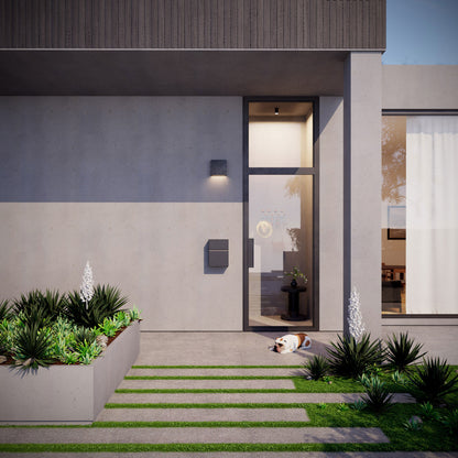 Wall-mounted mailbox - LEON by Bravios in Black mounted on a modern home entrance with a landscaped front yard.